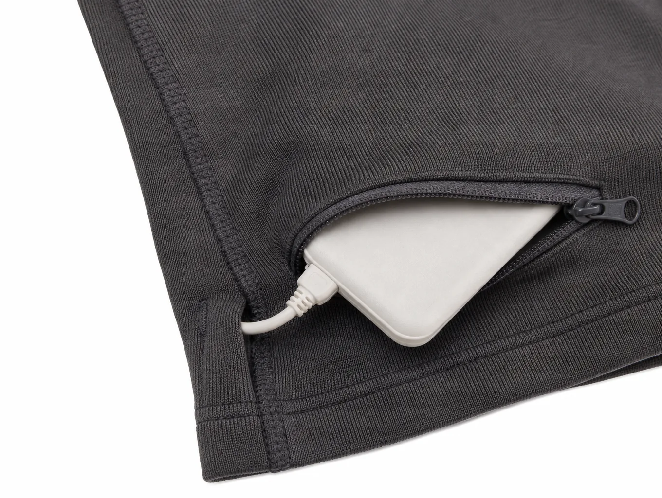 Close-up of the concealed zip battery pocket with a flat pouch and the cable connector entering the side seam