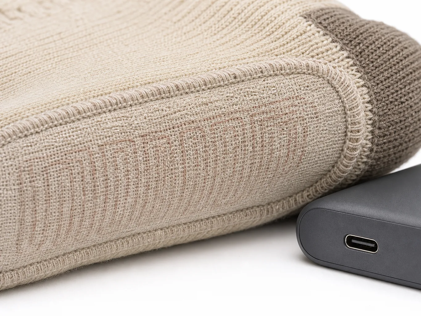 Close-up of the sole area of a heated sock showing the laminated heating element and a slim battery pack with a USB-C socket