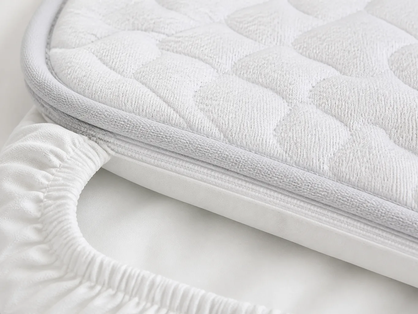 Close-up of the quilted knit surface, bound corner, hidden top zipper and elasticated skirt folded back over the smooth waterproof backing